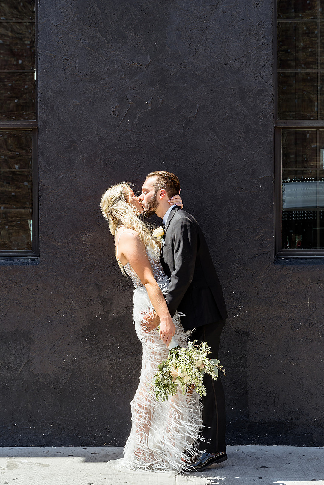 Eine schwarze Hausfassade bildet den perfekten Hintergrund für ein Hochzeitsfoto