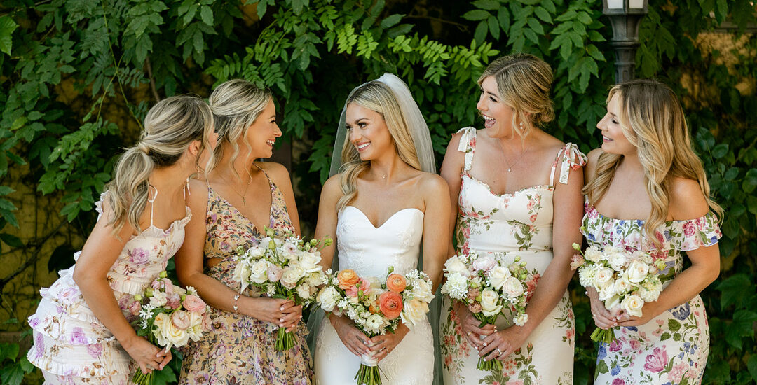 Brautjungfern in floralen Kleidern sehen sommerlich aus